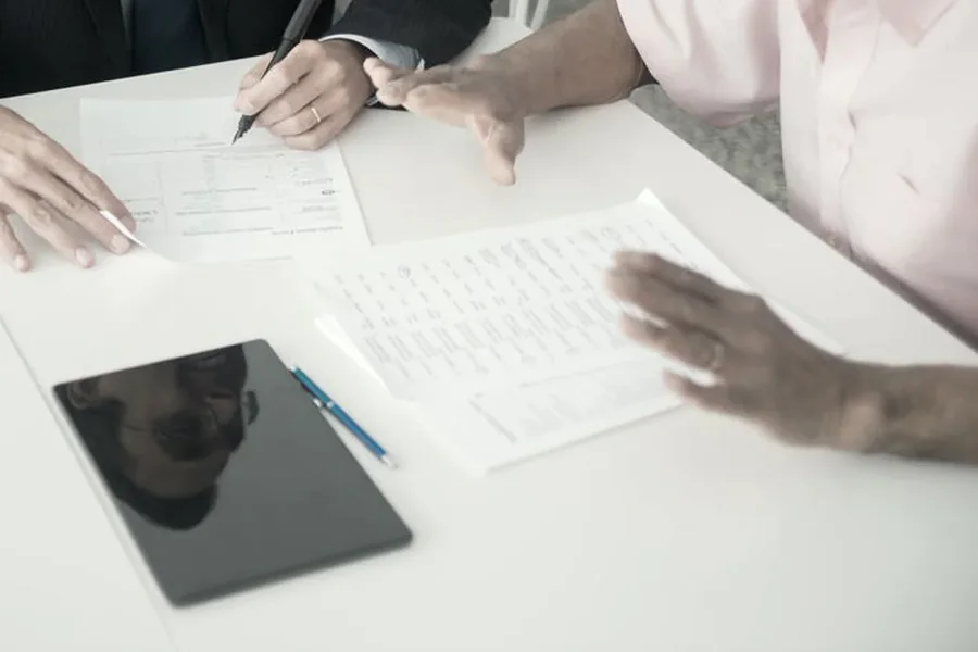 Dues persones revisant i signant documents en una taula