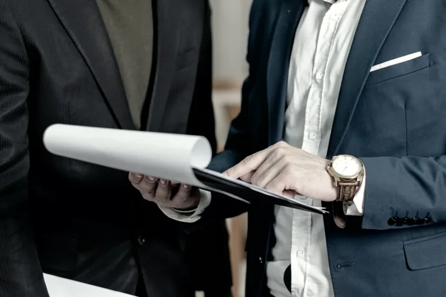 Dues persones amb vestit revisant els papers d'una carpeta